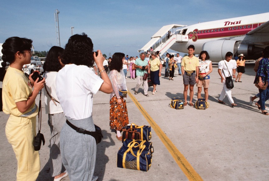1980年代開始外遊愈見普及,圖片攝於1989年,一個香港旅行團剛抵達泰國機場。(圖片來源:Getty) 1980年代開始外遊愈見普及,圖片攝於1989年,一個香港旅行團剛抵達泰國機場。(圖片來源:Getty)